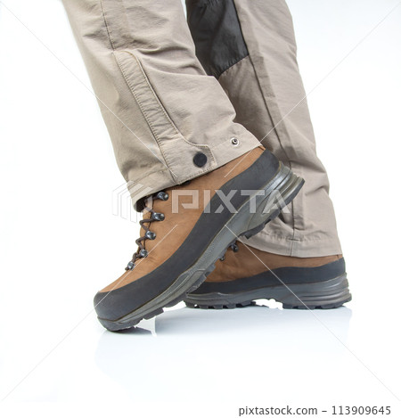 Trekking boots for hiking on the legs of a tourist on a white background 113909645