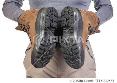 Tourist advertises and shows trekking boots. Clothing for tourism and travel Tourist advertises and shows trekking boots. Clothing for tourism and travel 113909673