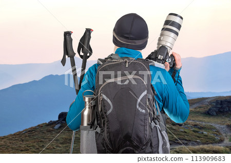 male tourist photographer with a backpack looks at the beauty of nature in the mountains 113909683