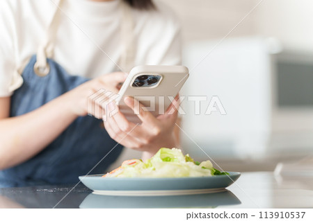 A woman taking a picture of cooking on a smartphone 113910537
