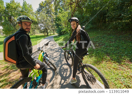 A sweet couple, adorned in cycling gear, rides their bicycles, their hands interlocked in a romantic embrace, capturing the essence of love, adventure, and joy on a sunlit path A sweet couple, adorned in cycling gear, rides their bicycles, their hands interlocked in a romantic embrace, capturing the essence of love, adventure, and joy on a sunlit path 113911049