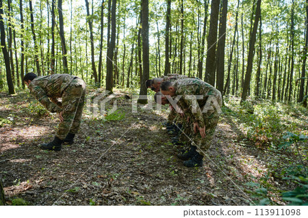 A dedicated group of soldiers engages in Islamic prayer amidst the challenging and perilous conditions of a military operation in dense forested areas 113911098