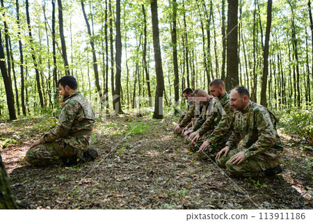 A dedicated group of soldiers engages in Islamic prayer amidst the challenging and perilous conditions of a military operation in dense forested areas A dedicated group of soldiers engages in Islamic prayer amidst the challenging and perilous conditions of a military operation in dense forested areas 113911186