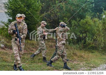 A group of elite soldiers leads captives through a military camp, showcasing a tense atmosphere of detention and security operations 113911204