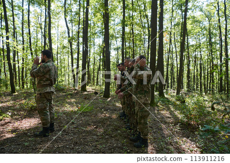 A dedicated group of soldiers engages in Islamic prayer amidst the challenging and perilous conditions of a military operation in dense forested areas A dedicated group of soldiers engages in Islamic prayer amidst the challenging and perilous conditions of a military operation in dense forested areas 113911216