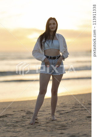 A woman is standing on the beach with her arms crossed and her hair wet 113911338
