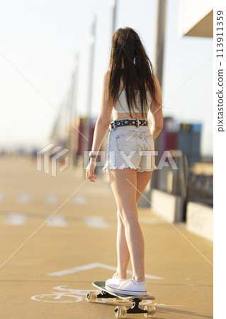 A girl is skateboarding on a sidewalk A girl is skateboarding on a sidewalk 113911359