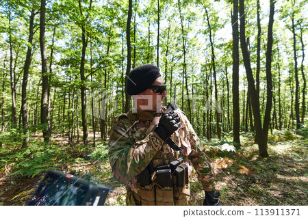 A military major employs a Motorola radio for seamless communication with his fellow soldiers during a tactical operation, showcasing professionalism and strategic coordination 113911371