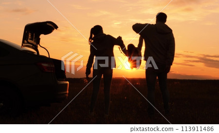 Silhouettes of having fun mom dad kid. Golden sunset, cheerful joyful family at holidays holding hands, lifting baby girl high in air, playing together. Fun active game. Traveling by car to nature. Silhouettes of having fun mom dad kid. Golden sunset, cheerful joyful family at holidays holding hands, lifting baby girl high in air, playing together. Fun active game. Traveling by car to nature. 113911486
