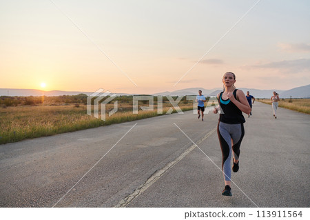 A diverse group of runners trains together at sunset. A diverse group of runners trains together at sunset. 113911564