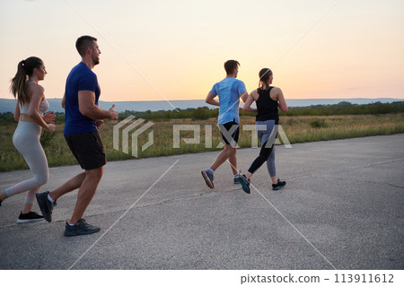 A diverse group of runners trains together at sunset. 113911612