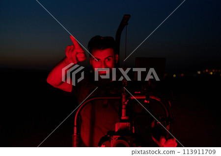 Nighttime Capture: Professional Videographer Films Athletes Running in Red-Lit Darkness 113911709