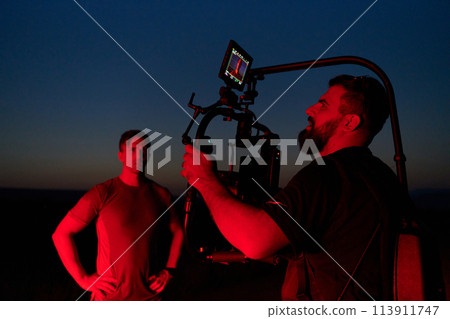 Nighttime Capture: Professional Videographer Films Athletes Running in Red-Lit Darkness 113911747