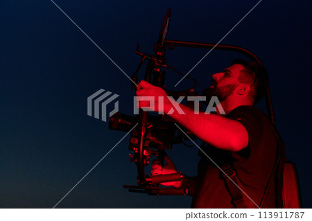 Nighttime Capture: Professional Videographer Films Athletes Running in Red-Lit Darkness 113911787
