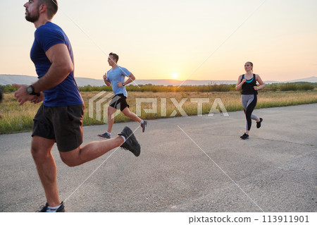 A diverse group of runners trains together at sunset. 113911901