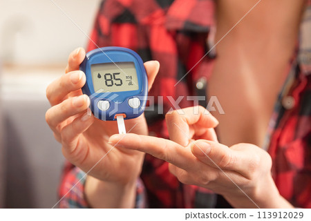 Woman using a glucose monitor. Diabetic disease 113912029