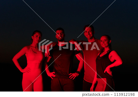 Diverse Athletes Unwind: Post-Marathon Rest Under Red Nighttime Glow. Diverse Athletes Unwind: Post-Marathon Rest Under Red Nighttime Glow. 113912198