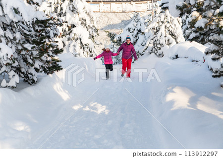 A Mother and Daughter's Blissful Run Along a Snowy Winter Path 113912297