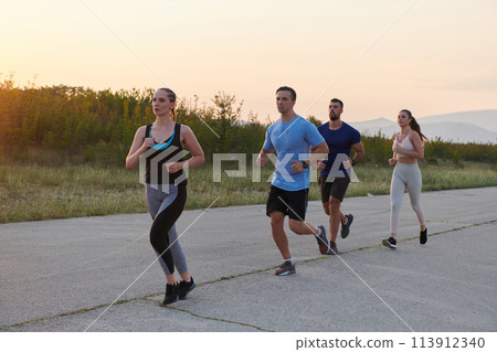 A diverse group of runners trains together at sunset. A diverse group of runners trains together at sunset. 113912340