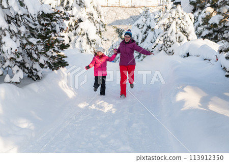 A Mother and Daughter's Blissful Run Along a Snowy Winter Path 113912350