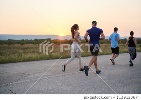 A diverse group of runners trains together at sunset. A diverse group of runners trains together at sunset. 113912367