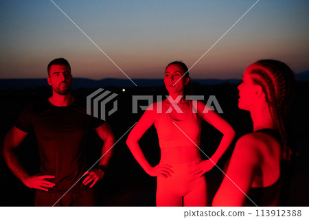 Diverse Athletes Unwind: Post-Marathon Rest Under Red Nighttime Glow. 113912388