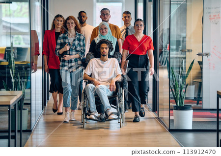 A diverse group of young business people congregates within a modern startup's glass-enclosed office, featuring inclusivity with a person in a wheelchair, an African American young man, and a hijab A diverse group of young business people congregates within a modern startup's glass-enclosed office, featuring inclusivity with a person in a wheelchair, an African American young man, and a hijab 113912470