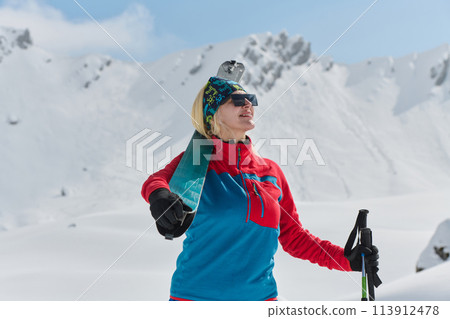 A professional woman skier rejoices after successfully climbing the snowy peaks of the Alps 113912478