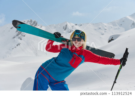 A professional woman skier rejoices after successfully climbing the snowy peaks of the Alps 113912524