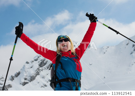 A professional woman skier rejoices after successfully climbing the snowy peaks of the Alps 113912541