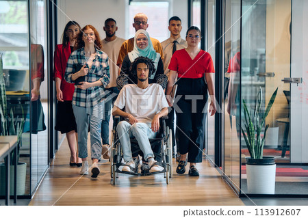 A diverse group of young business people congregates within a modern startup's glass-enclosed office, featuring inclusivity with a person in a wheelchair, an African American young man, and a hijab A diverse group of young business people congregates within a modern startup's glass-enclosed office, featuring inclusivity with a person in a wheelchair, an African American young man, and a hijab 113912607
