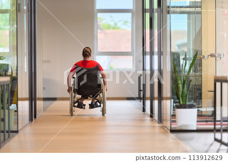 A modern young businesswoman in a wheelchair is surrounded by an inclusive workspace with glass-walled offices, embodying determination and innovation in the business world A modern young businesswoman in a wheelchair is surrounded by an inclusive workspace with glass-walled offices, embodying determination and innovation in the business world 113912629