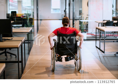 A modern young businesswoman in a wheelchair is surrounded by an inclusive workspace with glass-walled offices, embodying determination and innovation in the business world A modern young businesswoman in a wheelchair is surrounded by an inclusive workspace with glass-walled offices, embodying determination and innovation in the business world 113912765