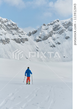 A Skier Scales a Treacherous Alpine Peak 113912843