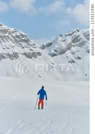 A Skier Scales a Treacherous Alpine Peak 113912890