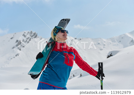 A professional woman skier rejoices after successfully climbing the snowy peaks of the Alps 113912979