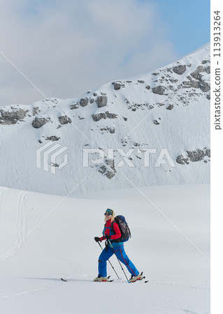 A professional woman skier rejoices after successfully climbing the snowy peaks of the Alps 113913264