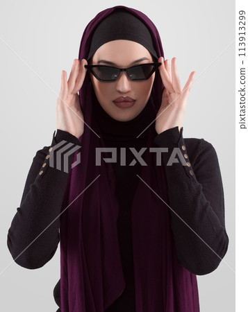 Portrait of beautiful stylish young muslim woman wearing black hijab and sunglasses as modern eastern fashion concept posing on white background. 113913299