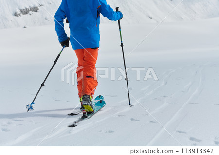 A Skier Scales a Treacherous Alpine Peak 113913342