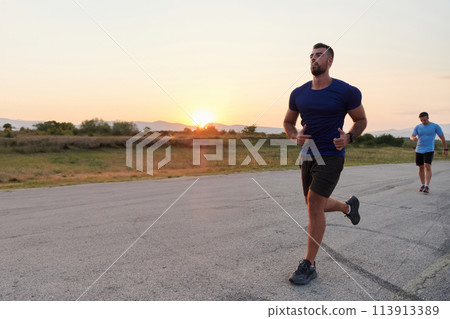 A diverse group of runners trains together at sunset. 113913389