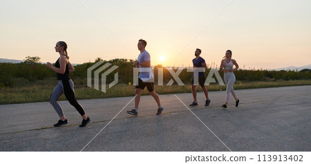 A diverse group of runners trains together at sunset. A diverse group of runners trains together at sunset. 113913402