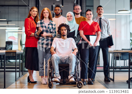 A diverse group of young business people walking a corridor in the glass-enclosed office of a modern startup, including a person in a wheelchair and a woman wearing a hijab A diverse group of young business people walking a corridor in the glass-enclosed office of a modern startup, including a person in a wheelchair and a woman wearing a hijab 113913481