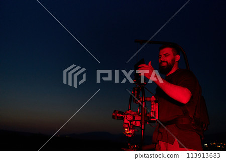 Nighttime Capture: Professional Videographer Films Athletes Running in Red-Lit Darkness 113913683