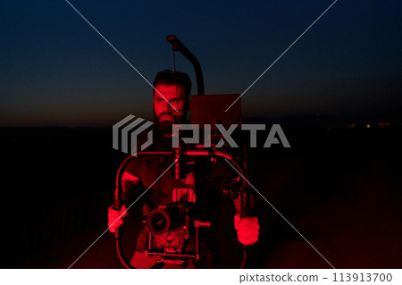 Nighttime Capture: Professional Videographer Films Athletes Running in Red-Lit Darkness 113913700