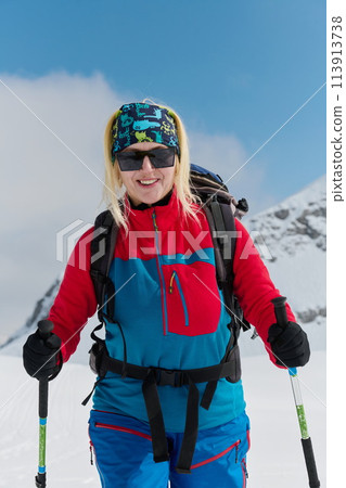 A professional woman skier rejoices after successfully climbing the snowy peaks of the Alps 113913738