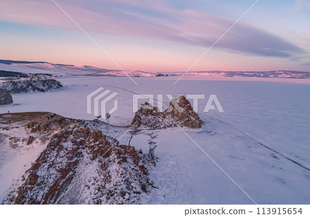 Aerial shot of a Shamanka rock on Olkhon island at sunset. Winter landscape. Popular touristic destination. Natural landmark. Panoramic view 113915654