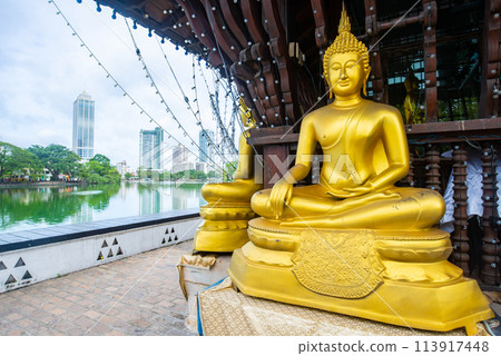 Golden Buddha statue in Seema Malaka buddhist temple on Beira Lake in Colombo, Sri Lanka. Colombo is the commercial capital and largest city of Sri Lanka. 113917448