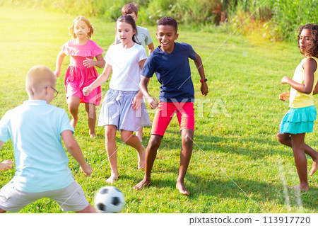Kids running through grass and playing football Kids running through grass and playing football 113917720