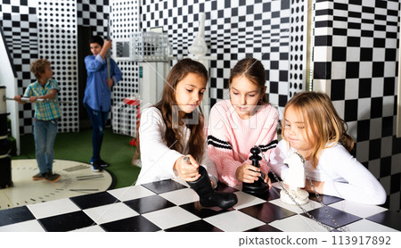 Tween girls solving conundrum in quest room stylized under chessboard 113917892