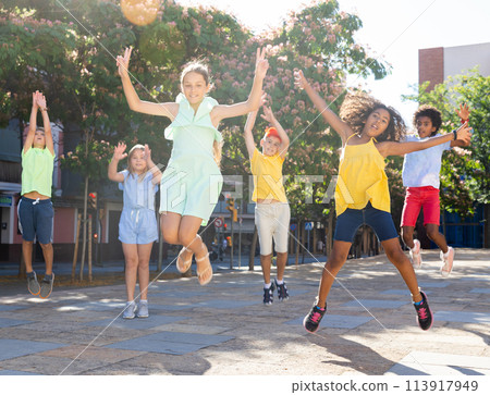 Cheerful preteen friends jumping on summer city street 113917949